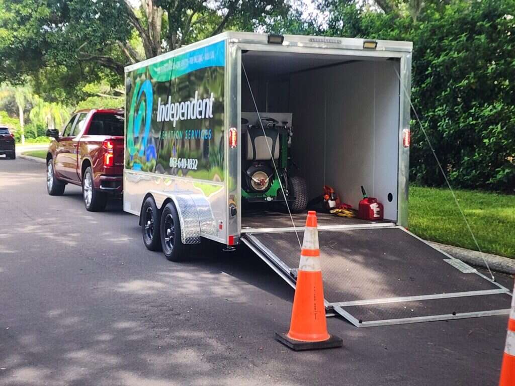 Independent Aeration Services enclosed trailer with logo wrap, ramp down at a Lakeland job